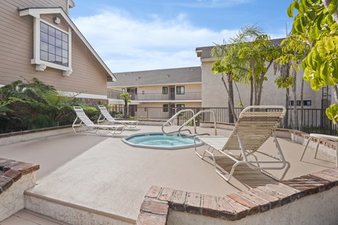 A pool with a hot tub and chairs in front of a house.