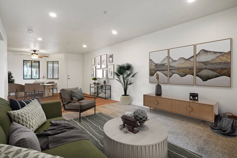 A living room with a green couch, a coffee table, and a painting on the wall.