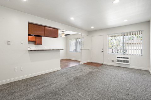 A spacious living room with a grey carpet and white walls.