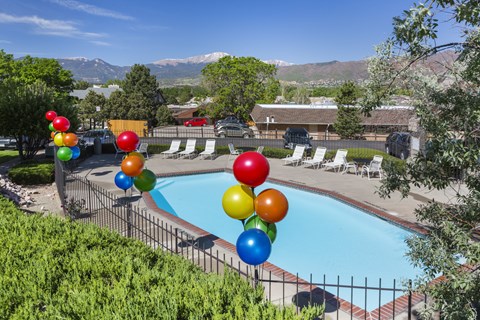 A pool surrounded by trees and balloons.