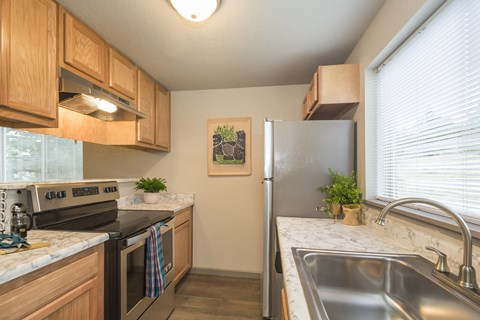 A kitchen with a refrigerator, sink, and stove.