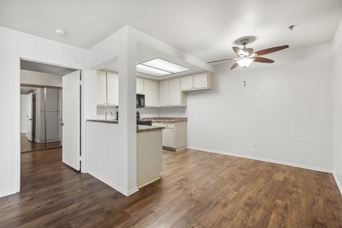 A kitchen with white cabinets and a wooden floor.