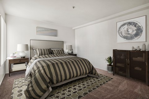 A bedroom with a large bed and a painting on the wall.
