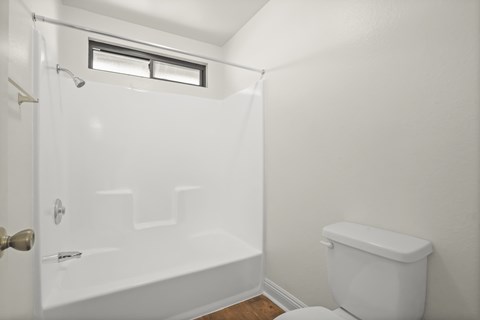 A white bathroom with a toilet, tub, and shower.