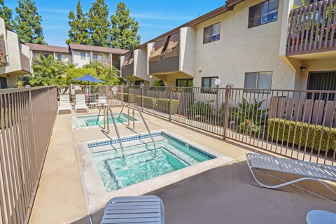 A pool with a slide in the middle of a patio surrounded by a fence.
