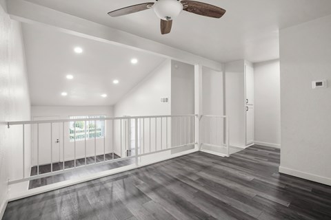 A spacious room with a ceiling fan and wooden flooring.