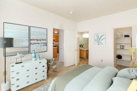 A bedroom with a large bed and a white dresser.