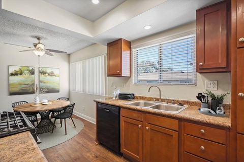 A kitchen with wooden cabinets and a black trash can.