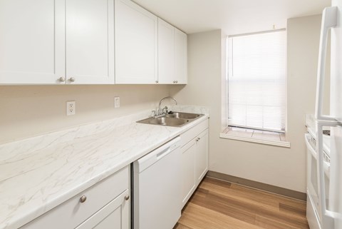 A kitchen with white cabinets and a marble countertop.