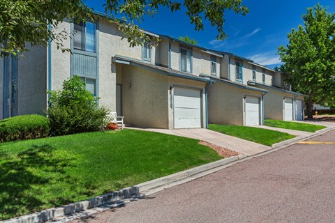 A row of apartment buildings with green lawns in front.