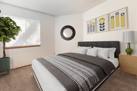 A bedroom with a large bed and a green plant.