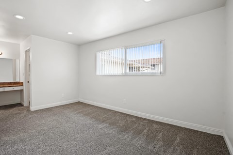 A room with a window and a carpeted floor.