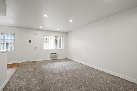 A room with a carpeted floor and a window with blinds.