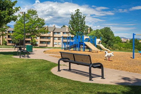 A playground with a slide and a bench in the foreground.