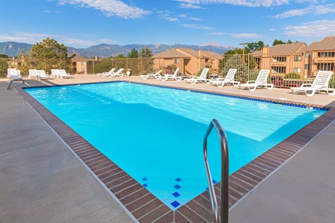A swimming pool with a ladder and sun loungers.
