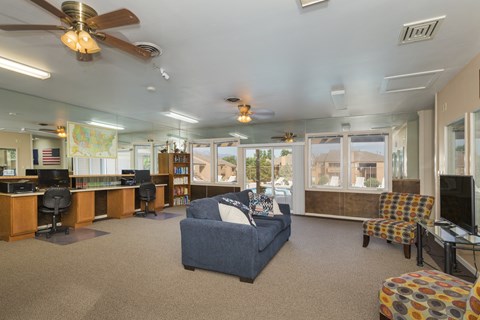 A spacious living room with a blue couch and a ceiling fan.