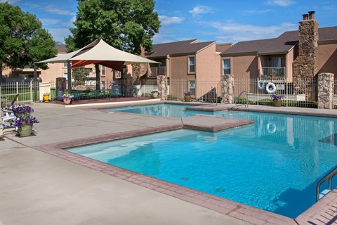 A swimming pool surrounded by a patio and a gazebo.