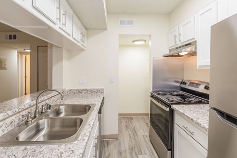 A kitchen with a stainless steel sink and white cabinets.