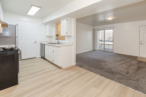 A kitchen with white cabinets and a black fridge.