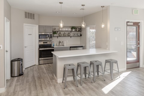 A kitchen with a white counter and grey stools.