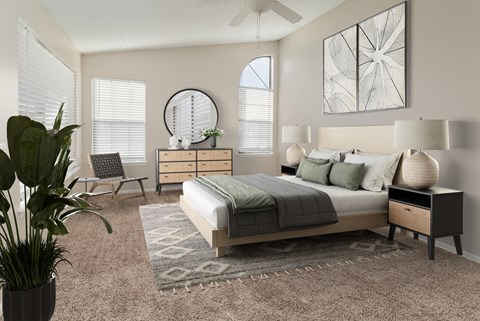 A bedroom with a large bed, a potted plant, and a mirror on the wall.