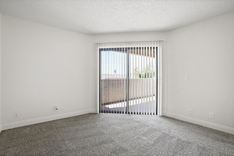 A room with a carpeted floor and a sliding glass door.