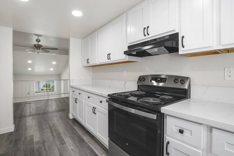 A modern kitchen with a black stove top oven and white cabinets.