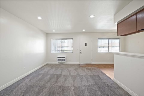 A spacious room with a grey carpet and white walls.