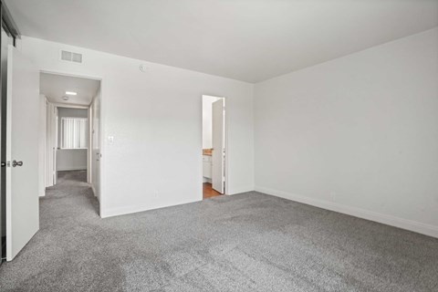A spacious room with a carpeted floor and white walls.
