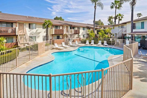 A pool surrounded by a fence and chairs.