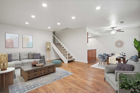 A living room with a staircase and a dining area.
