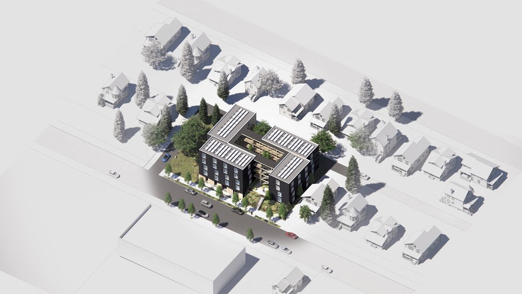 A model of a building with a black roof is surrounded by white houses and trees.