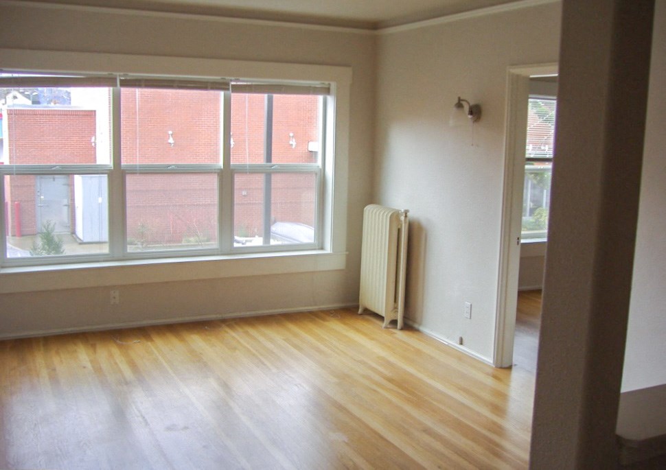 an empty living room with wooden floors and white walls
