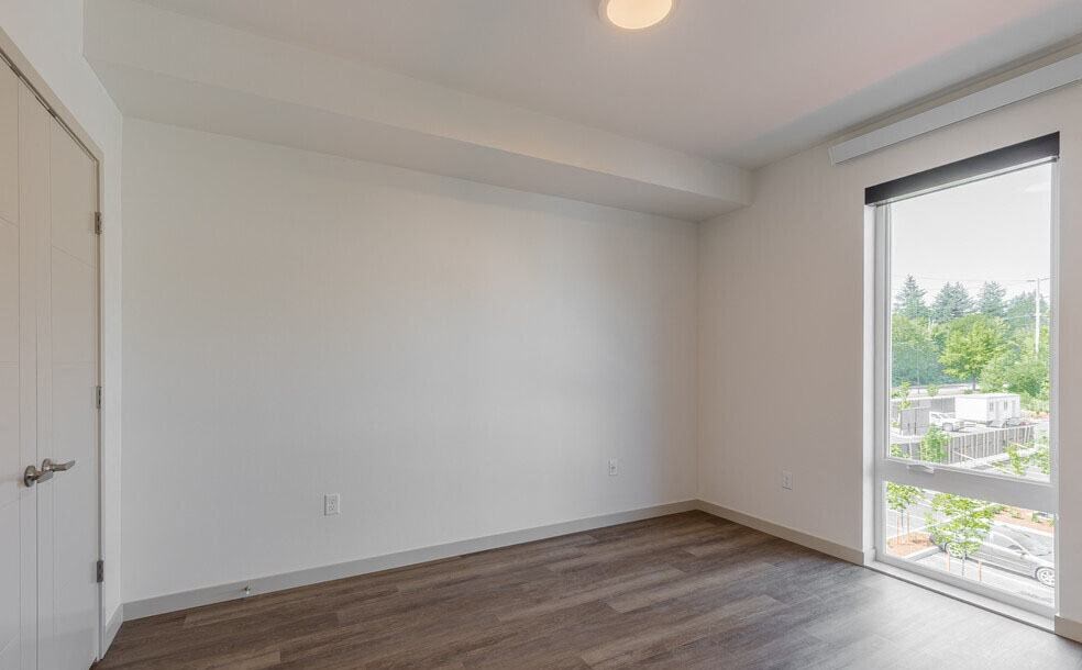 a bedroom with a large window and hardwood floors