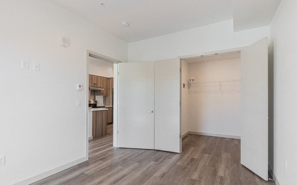 an empty room with a kitchen in the background