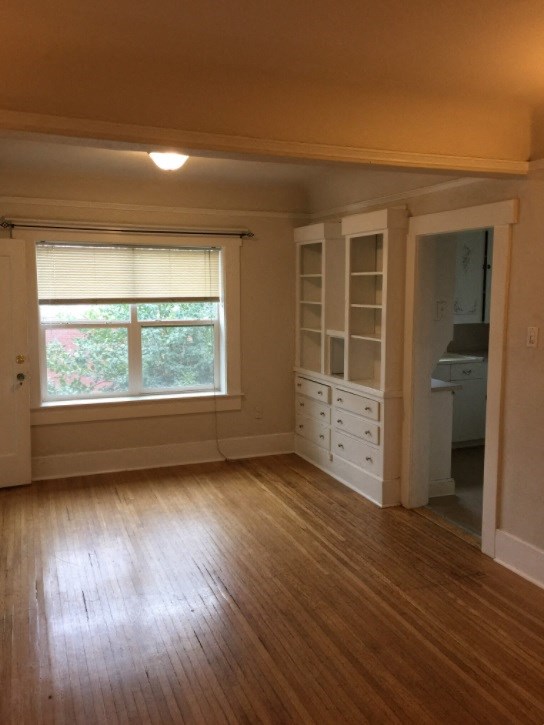an empty living room with wood floors and a window