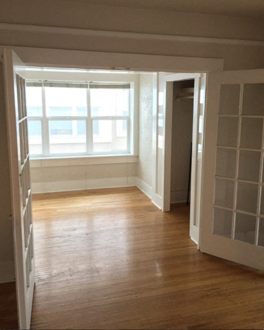 an empty room with a window and wooden floors