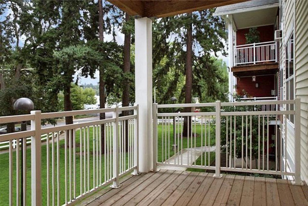 a porch with a wooden floor and white rails