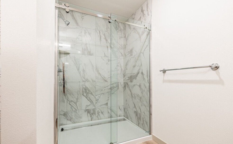 a bathroom with a glass shower door and a towel rack