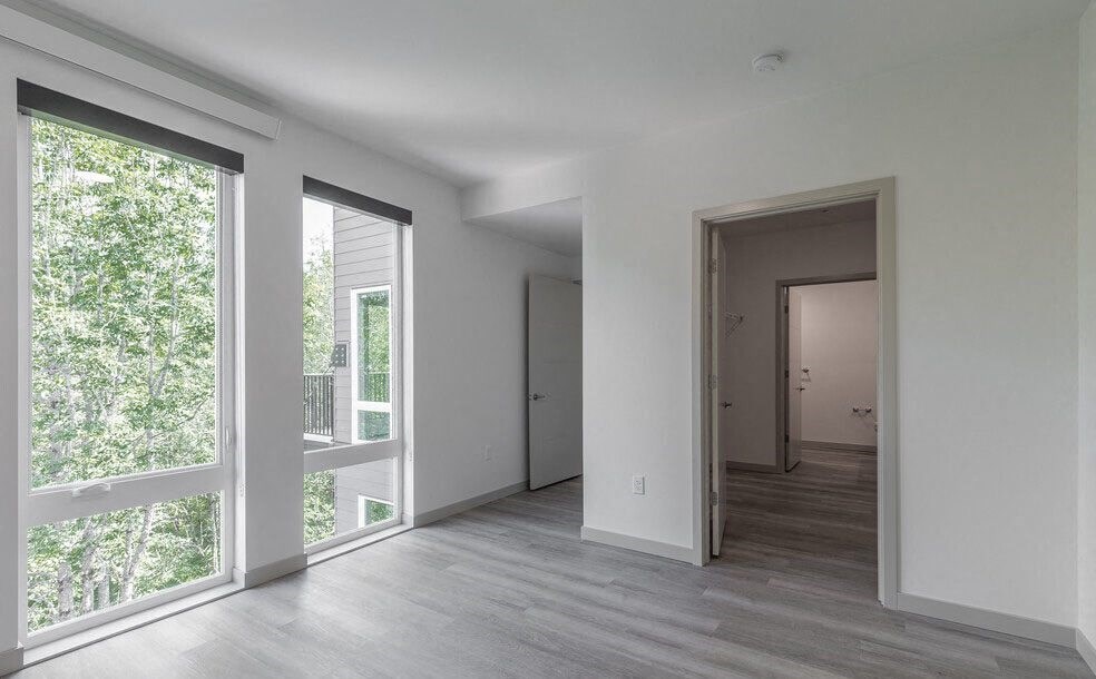 a bedroom with a large window and a door that leads to a hallway