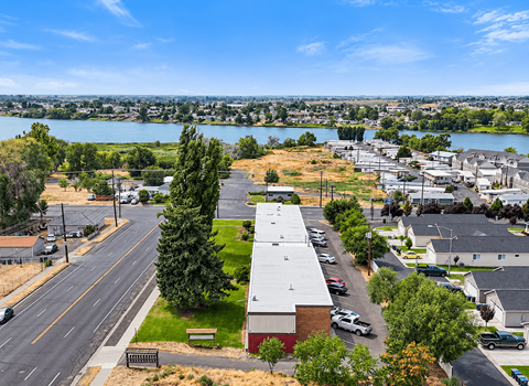A view of a street with cars and buildings with a lake in the background.