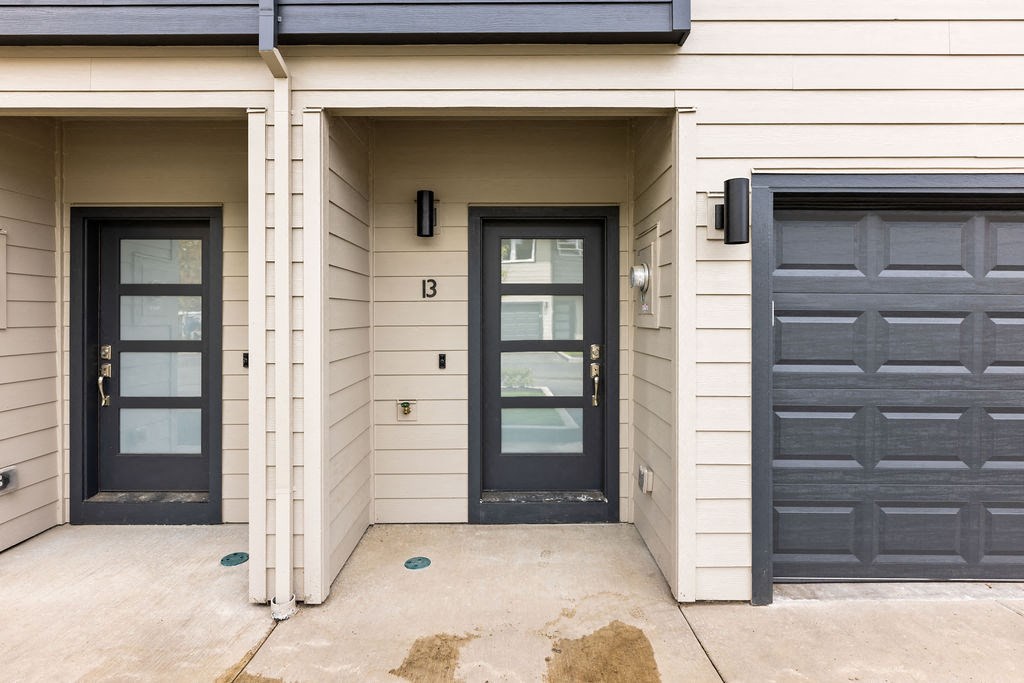 the front of a house with black doors and a sidewalk