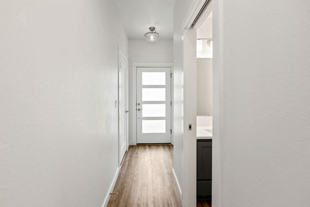 a hallway with white walls and a window and a door