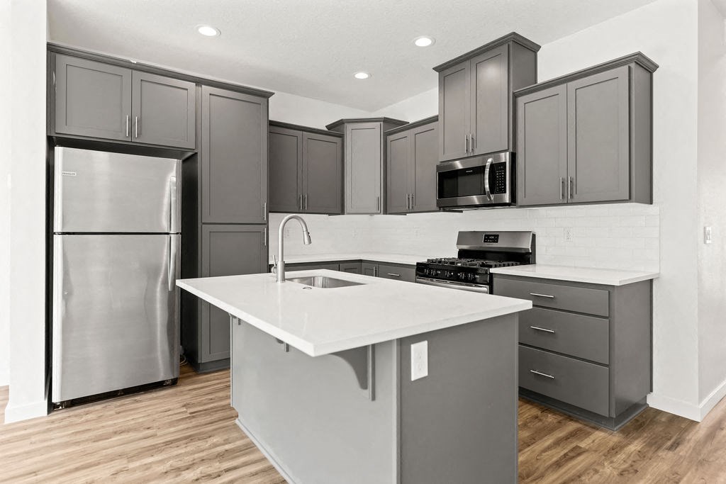 a kitchen with gray cabinets and a stainless steel refrigerator