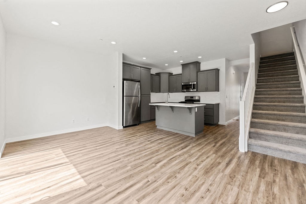 a living room with a staircase and a kitchen