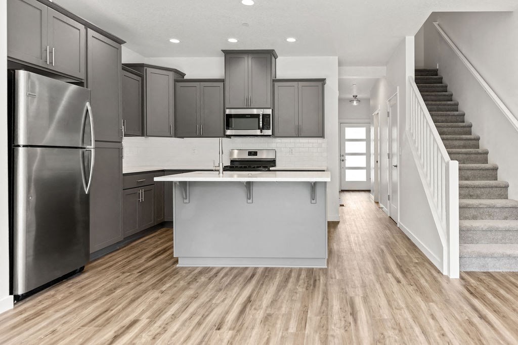 a kitchen with an island and a stainless steel refrigerator