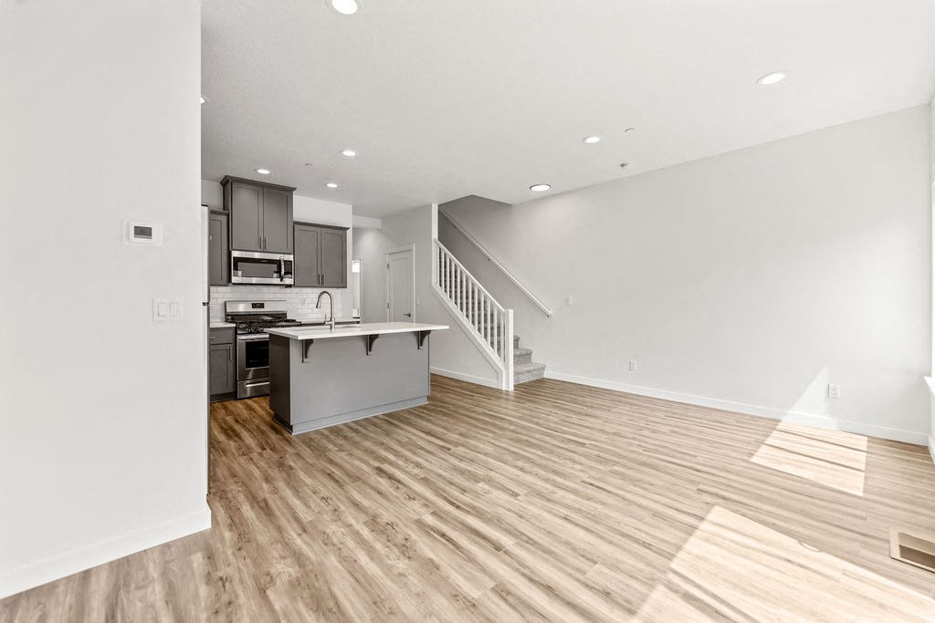 an empty living room with a kitchen and stairs