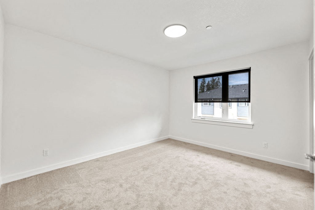 an empty bedroom with a window and carpet