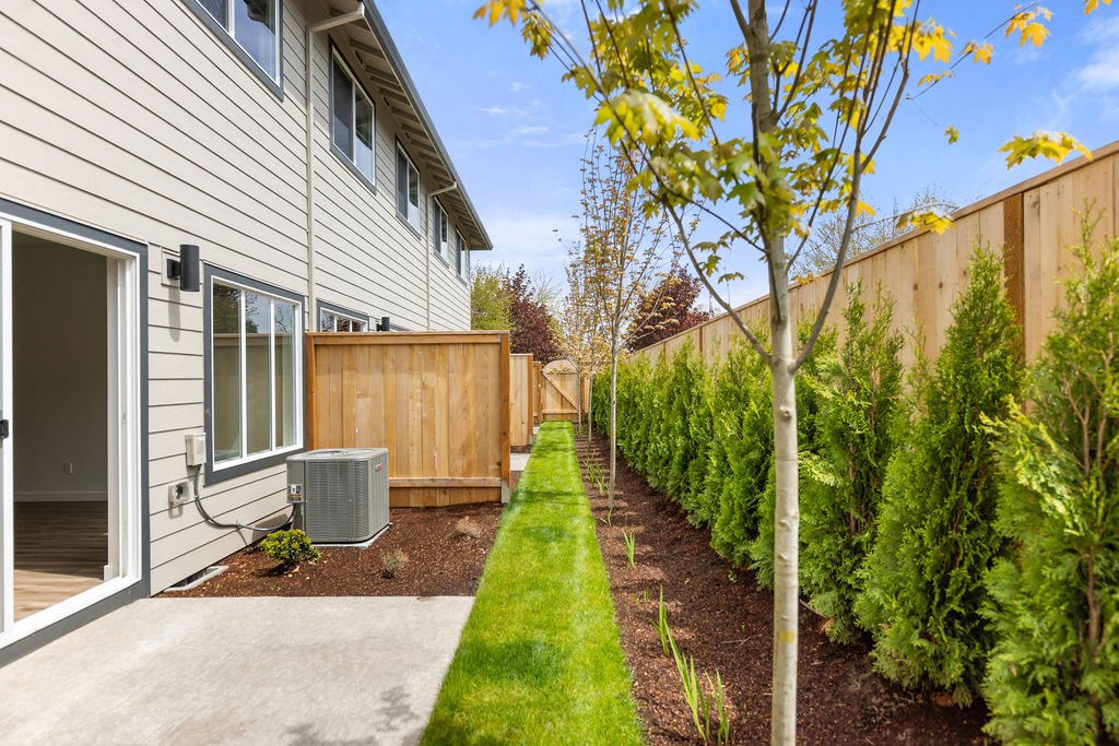 a yard with a wooden fence and a sidewalk next to a house
