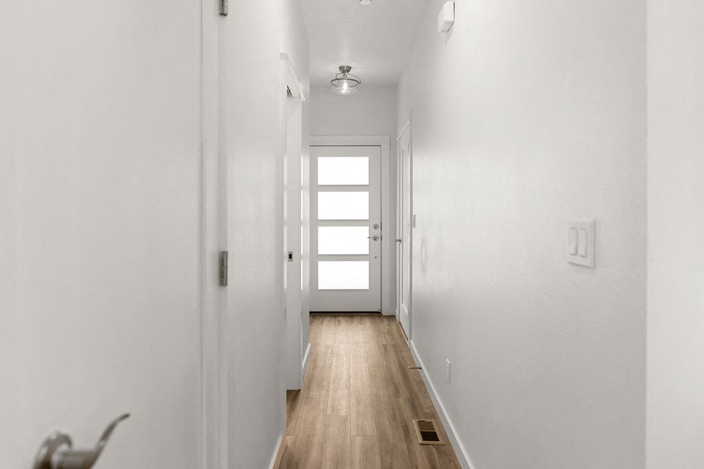 a long white hallway with a window and a door